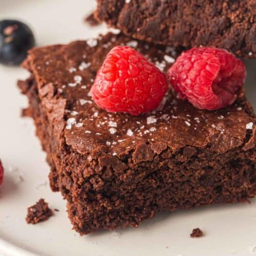 Rich chocolate brownie topped with fresh raspberries and sea salt crystals for dessert enhancement.