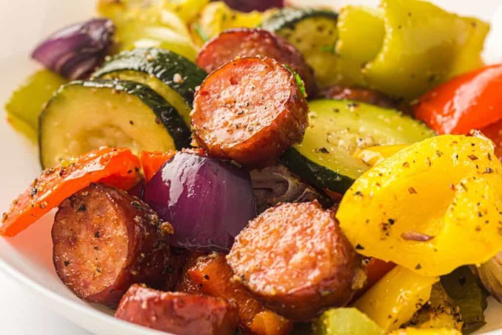 Close-up shot of the Sheet Pan Sausage & Roasted Vegetables on a white bowl.