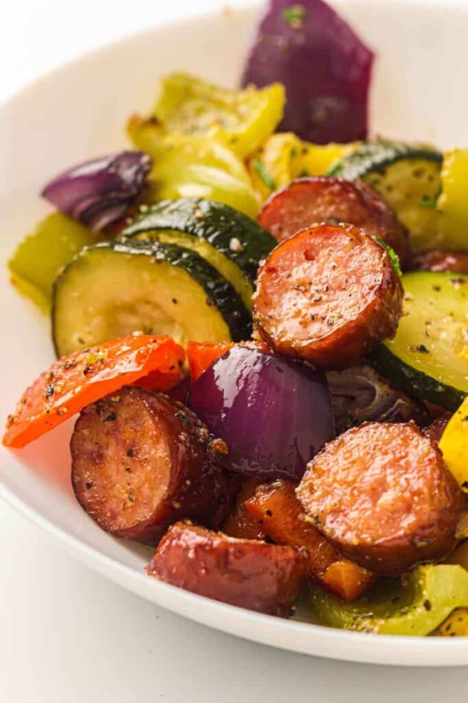 A white bowl filled with Sheet Pan Sausage & Roasted Vegetables.