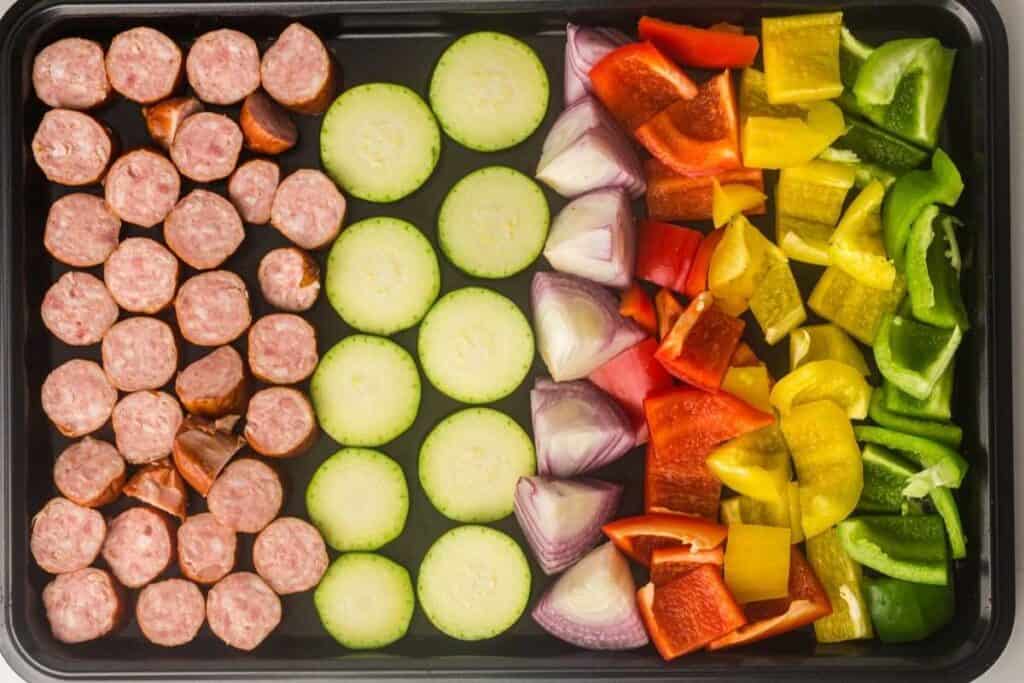 Add the sliced sausage, tucking pieces between the vegetables for even browning.