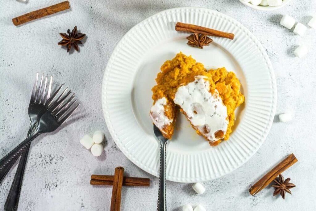 Bright image of creamy sweet potato casserole topped with marshmallows, garnished with cinnamon sticks and star anise for holiday desserts.