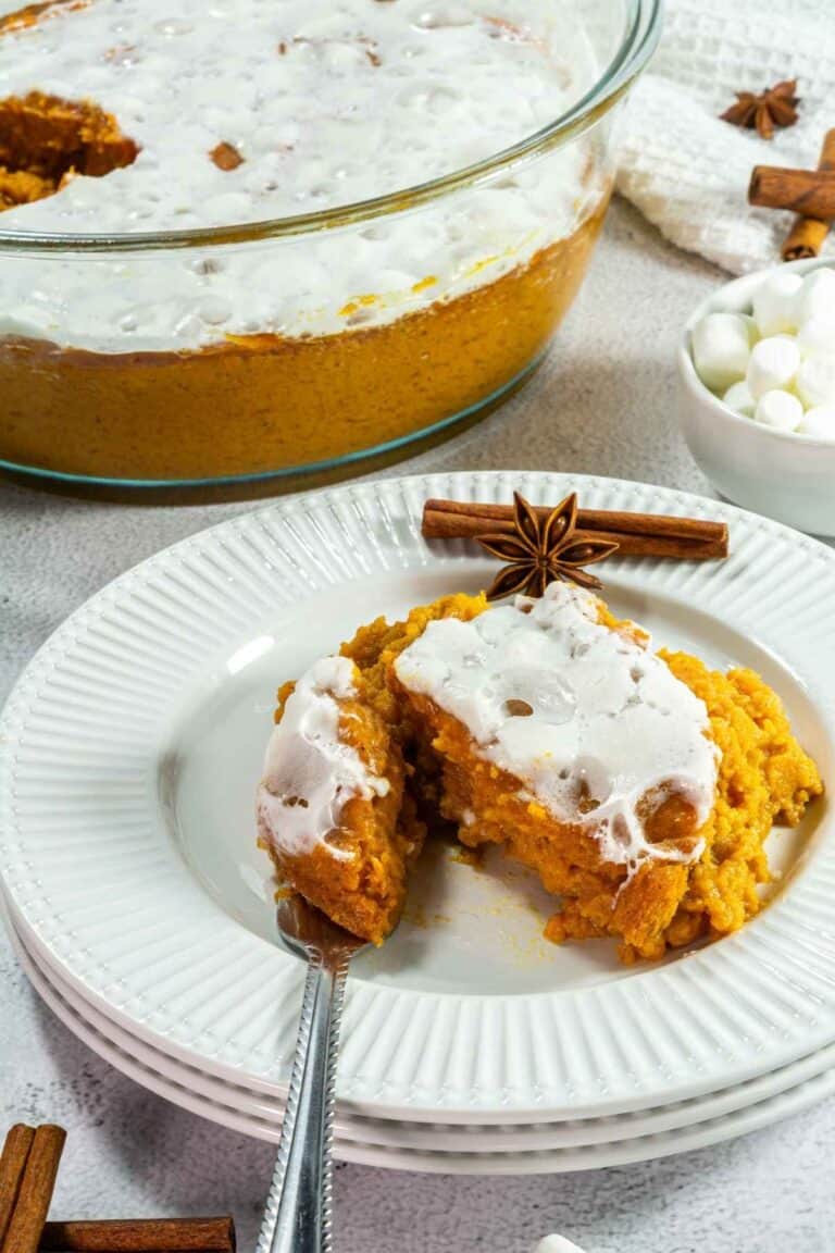 Delicious sweet potato casserole with marshmallow with whipped cream, served on a white plate.