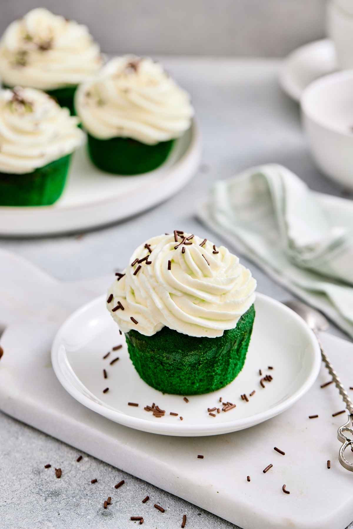 Delicious green matcha cupcake topped with creamy white frosting and chocolate sprinkles.