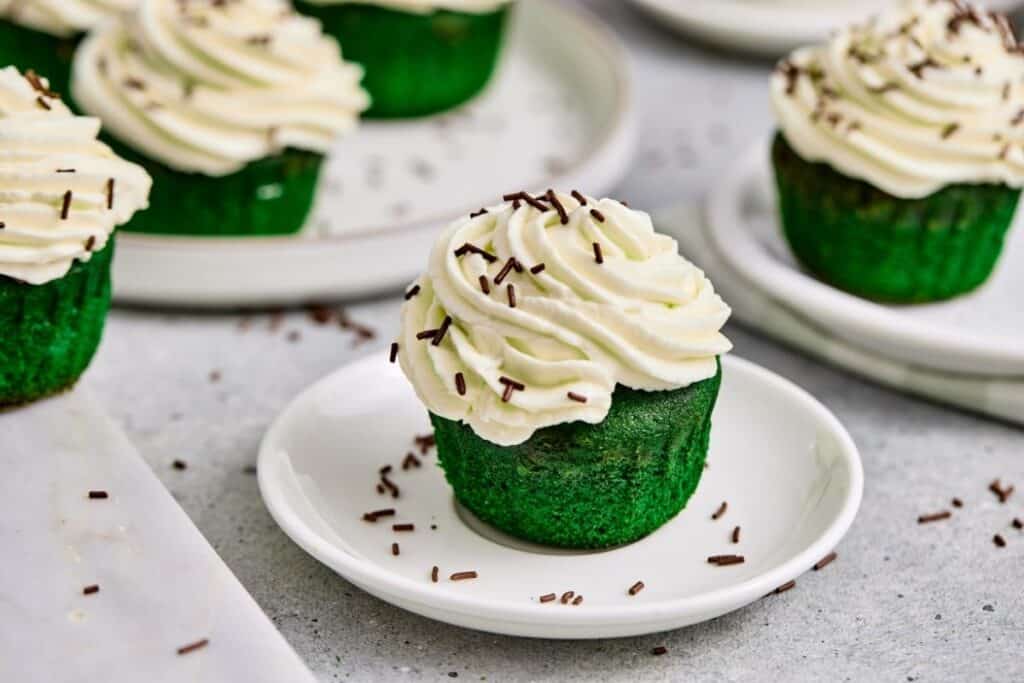 Delicious green matcha cupcake topped with creamy white frosting and chocolate sprinkles.