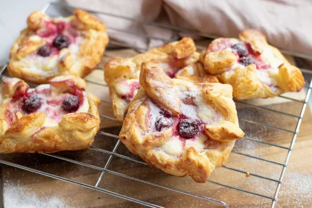 Five pieces of Danish Pastries with Cream Cheese & Cherries on a cooling rack.