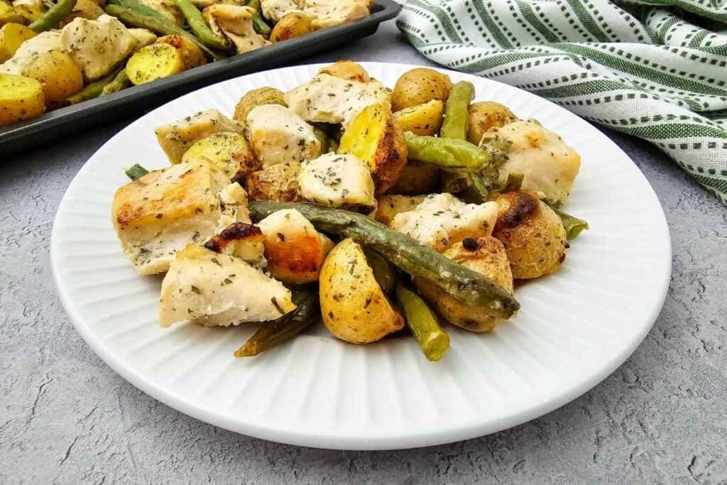 Close-up photo of healthy food with chicken, potatoes, and green beans on a white plate.