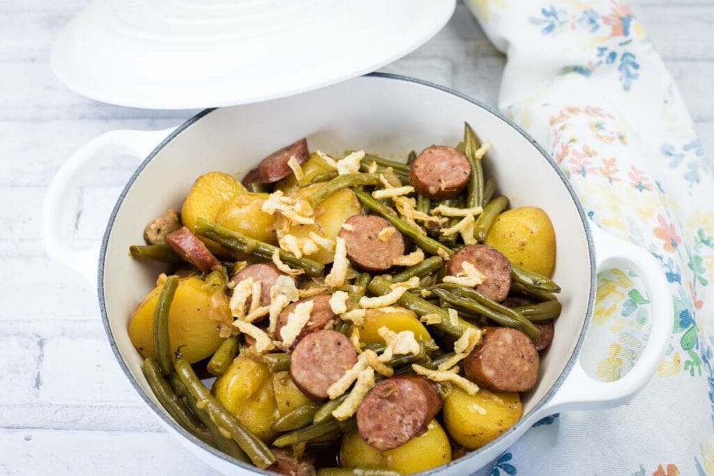 Delicious sausage and vegetable stew with potatoes, green beans, and cheese, perfect for a comfortin.