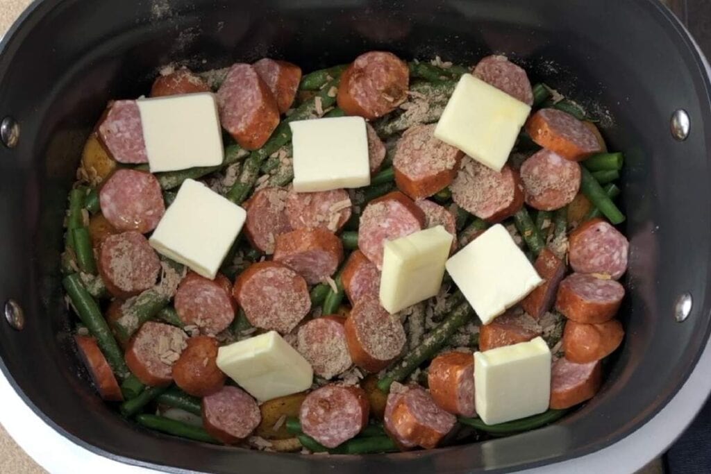 Sausage and vegetable stir-fry with cheese in a skillet, ready to cook.