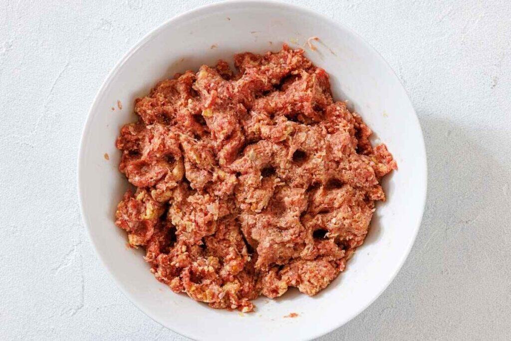 Add the ground beef, ground pork, egg, salt, pepper, nutmeg, and allspice to the bowl with the onion.