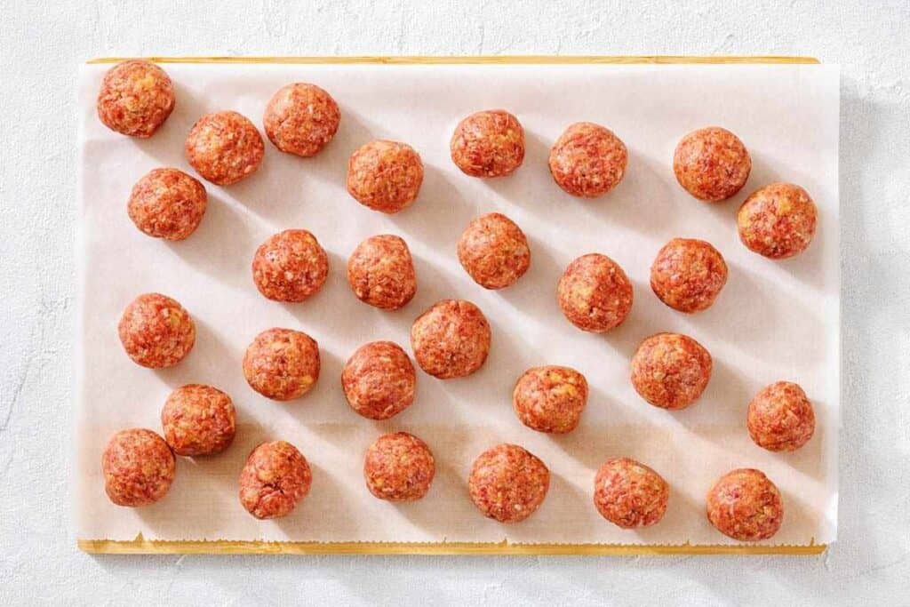 Roll gently into meatballs and place them on the baking sheet.