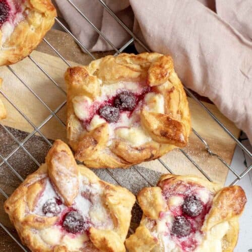 Three pieces of Danish Pastries with Cream Cheese & Cherries on a wire rack.