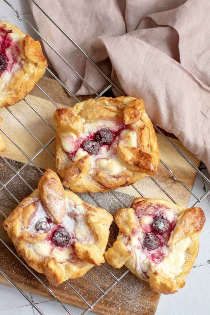 Three pieces of Danish Pastries with Cream Cheese & Cherries on a wire rack.
