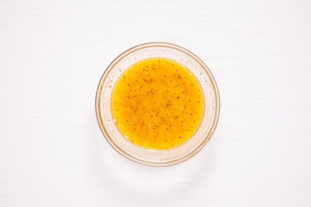 Mixture of melted butter, lemon juice, salt, black pepper, cayenne pepper, and garlic powder in a small bowl.