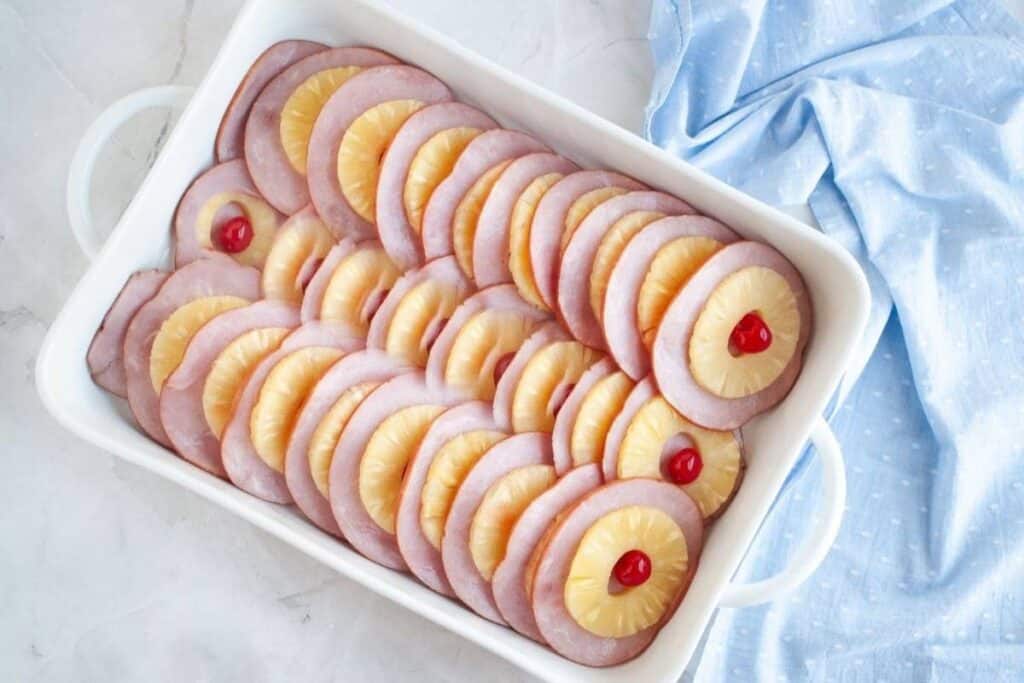 Place one pineapple ring on top of each ham slice and set a maraschino cherry in the center of each ring.