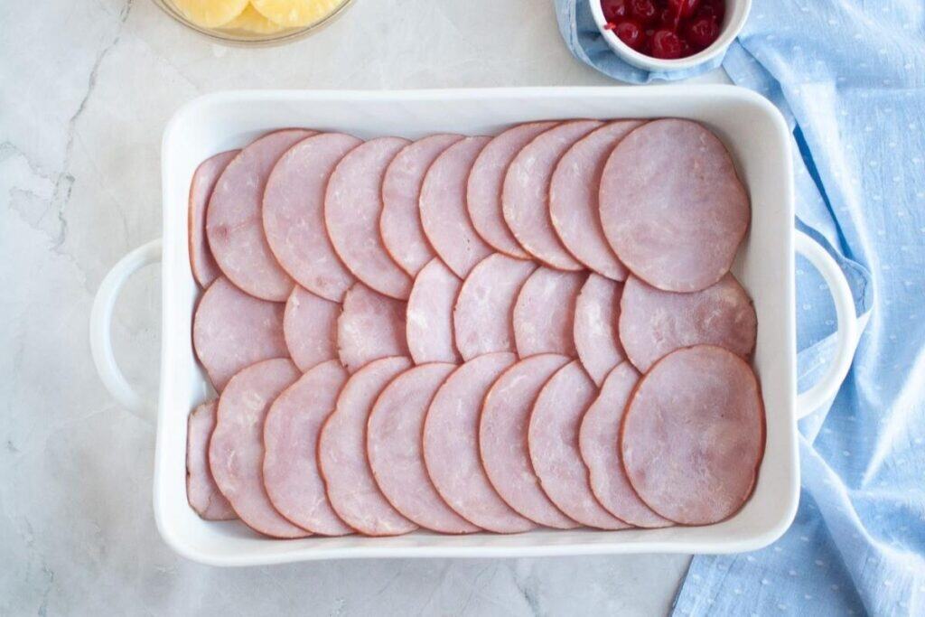Arrange the ham slices in a shallow baking dish.