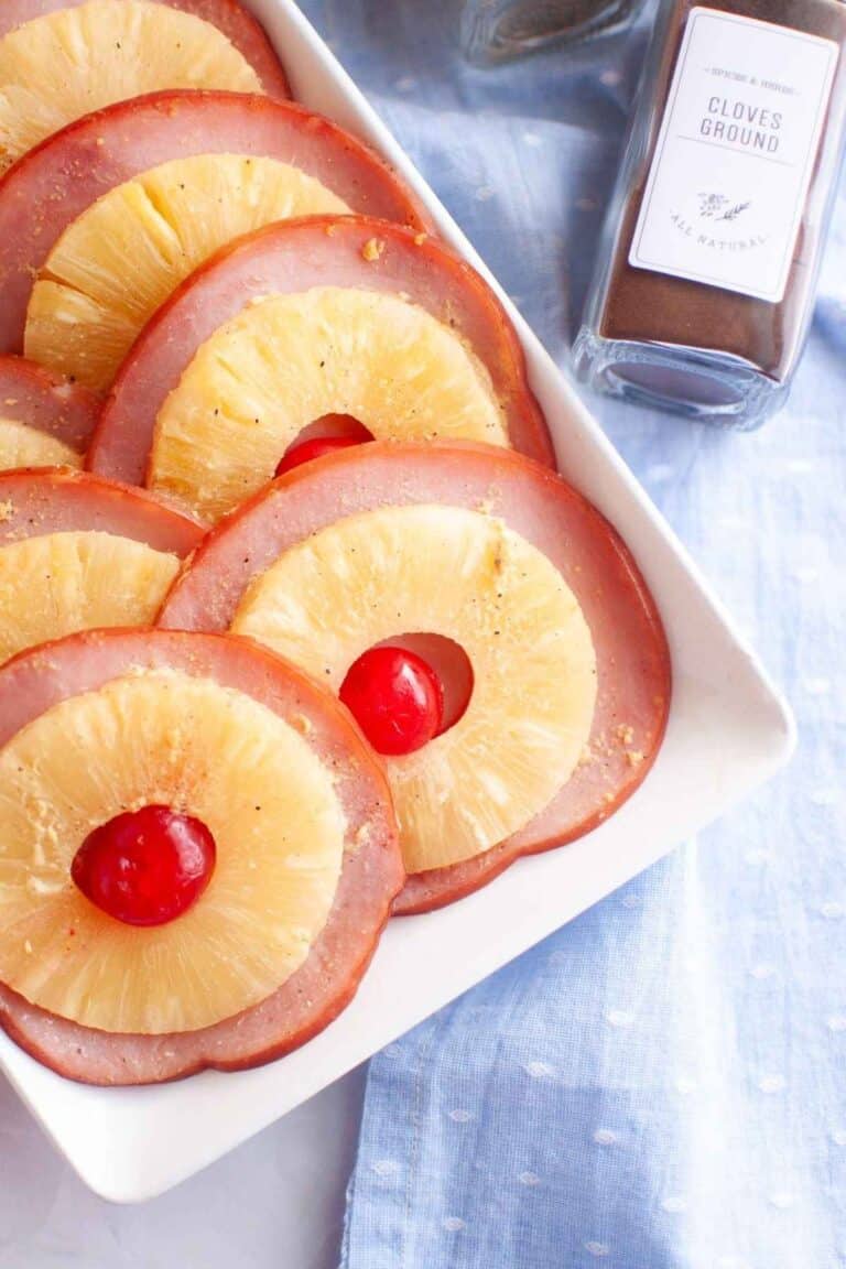 A white plate with slices of glazed ham is arranged neatly.
