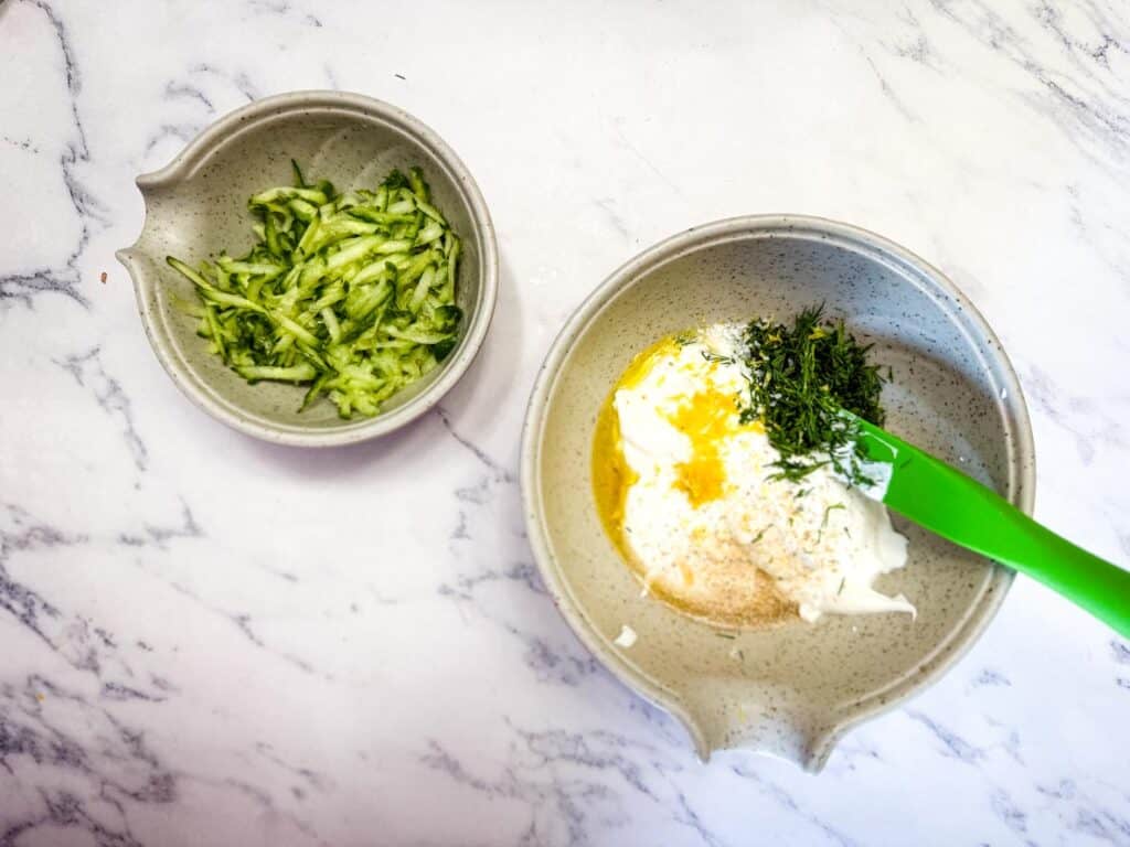 Add the cucumber to a bowl with the Greek yogurt, garlic, olive oil, honey, lemon zest if using, kosher salt, and chopped herbs.