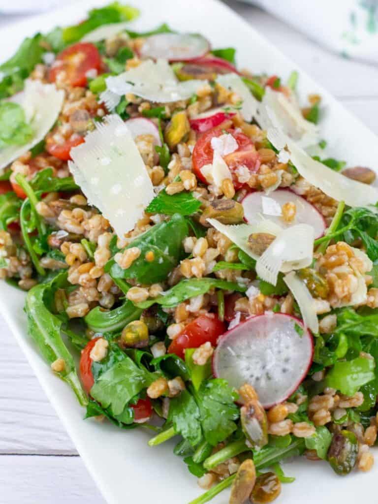 Copycat Charlie Bird&rsquo;s Farro Salad topped with a flaky salt on a white plate.