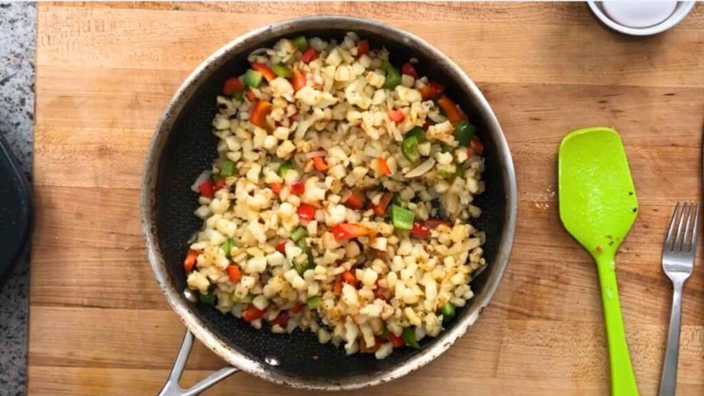 Once the hash browns are golden, add the onion and let it soften for a few minutes before stirring in the peppers with the rest of the seasoning.