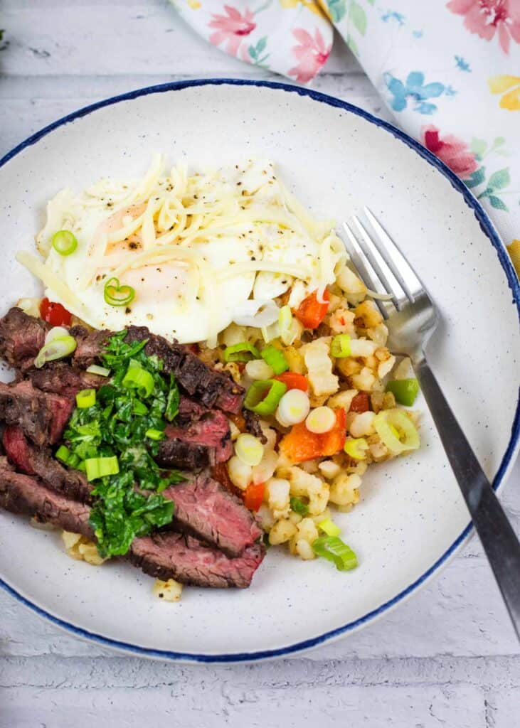 Top-down shot of Steak and Eggs Breakfast Bowl on a round white plate.