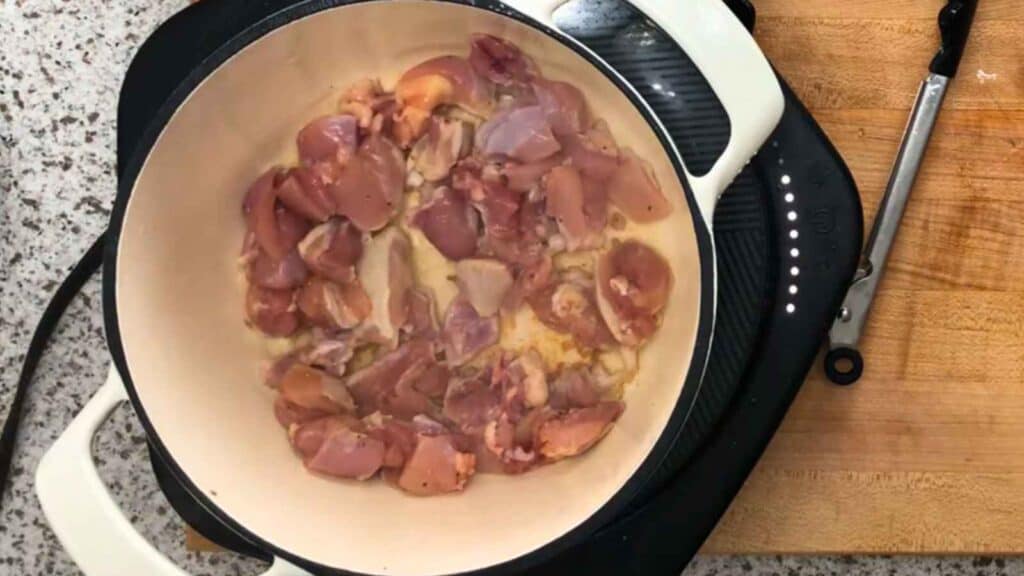 Season the chicken thighs with salt and pepper, then brown them in a hot Dutch oven for a few minutes per side.