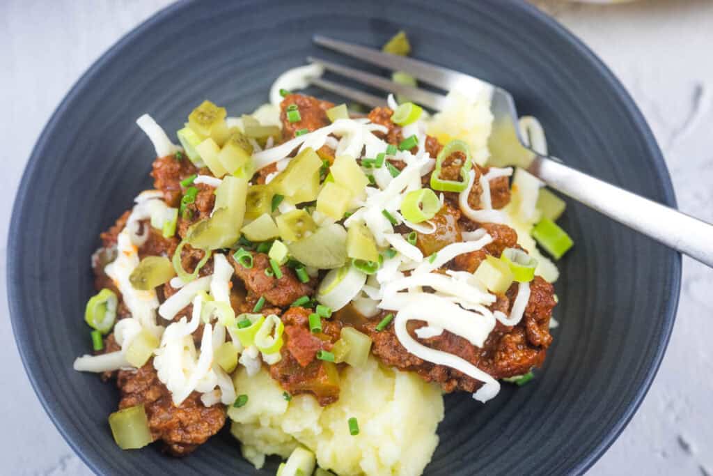 A close-up shot of Sloppy Joe Mashed Potato on a black bowl.
