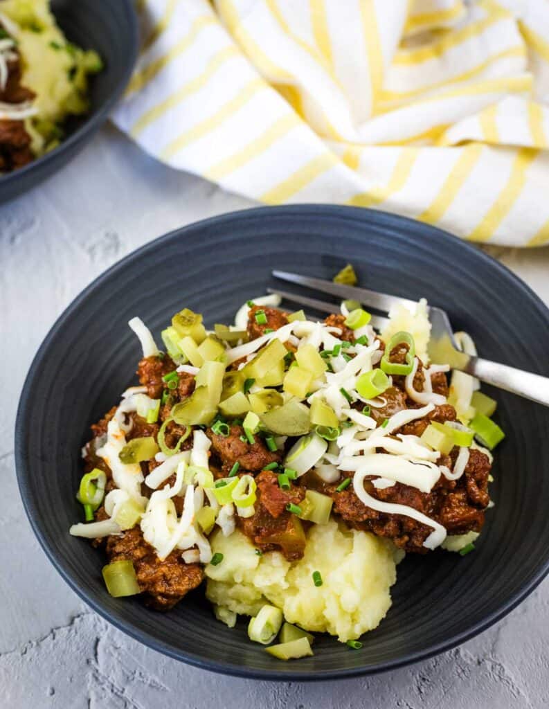 A bowl of Sloppy Joe Mashed Potato beside a fork.