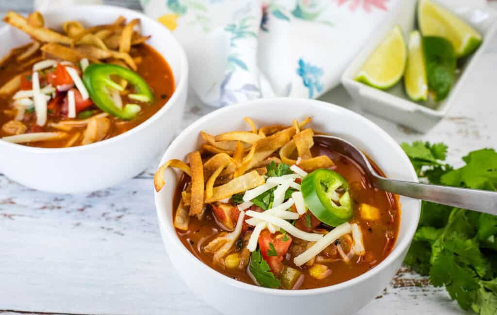 Close-up of chicken tortilla soup with cheese and jalapenos in a white bowl.
