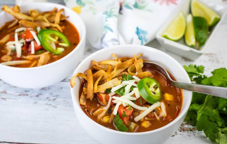 Close-up of chicken tortilla soup with cheese and jalapenos in a white bowl.