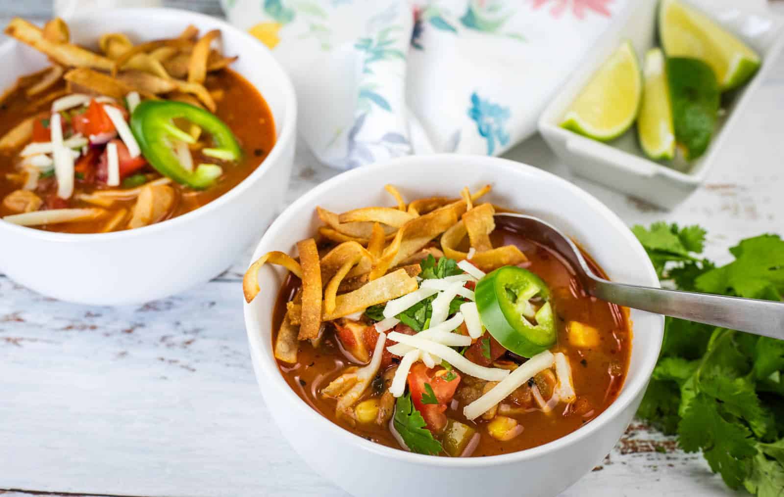 Close-up of chicken tortilla soup with cheese and jalapenos in a white bowl.